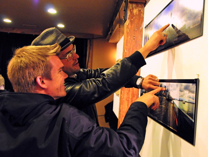At the Fremont Abbey, photographer Robertsen Ashman (in hat) compares two panoramas of downtown Seattle, part of the exhibit aEœUrban Landscapes: The Abstract Context Instigates.