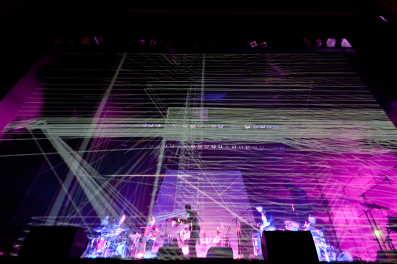 A mesh curtain displays animations in front of the band