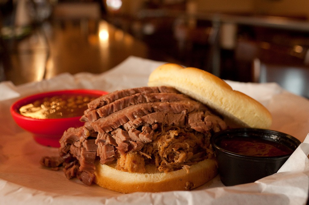 Beef brisket and pulled pork sandwich, with baked beans and sauce on the side.