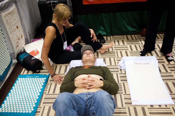 Jubal Byrne lays on a Spoonk Rider mat, which has hundreds of pointy spikes that stimulate bloodflow to your back, while Rebecca Knapman explains how it works during the Green Festival in Seattle, Wash., on Sunday, June 6, 2010.  (Photo by Matthew Williams for The Seattle Weekly)