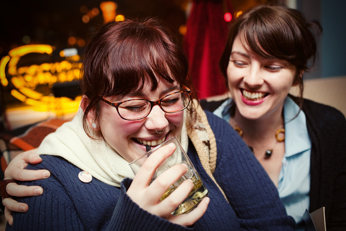 Heather giggles into her drink with Laurie.