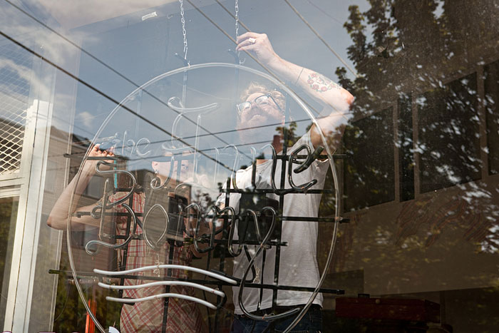 Coco & Spencer hang the Anne Bonney sign at its new location on Summit & Mercer.