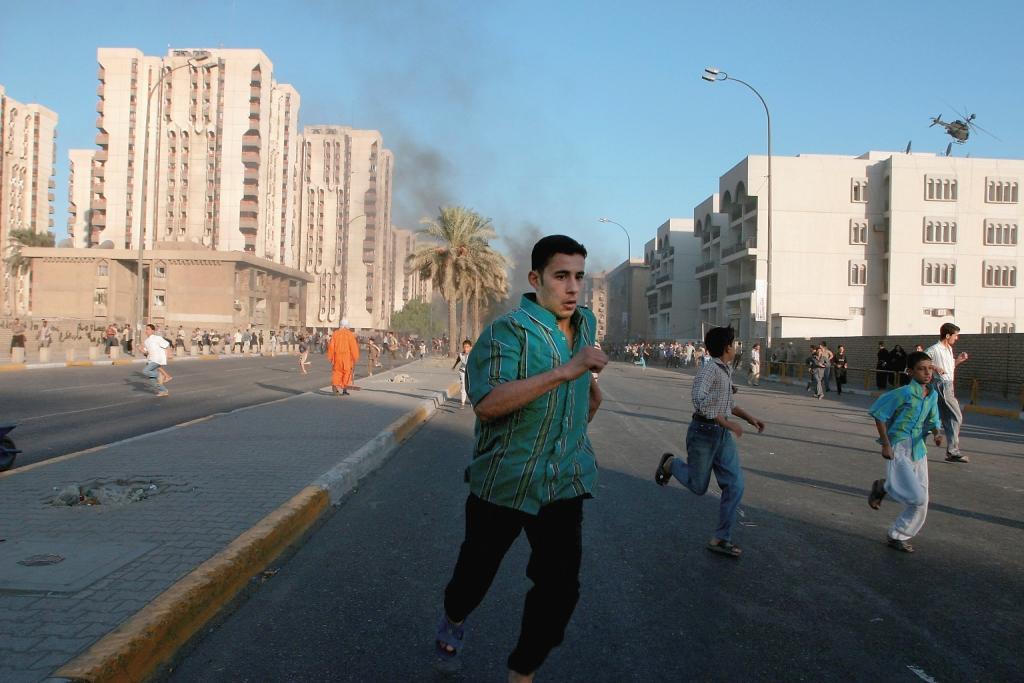 BAGHDAD, IRAQ - SEPTEMBER 12: Iraqi civilian run away as U.S. helicopters opened fire at civilians, in Haifa st. in Baghdad today September 12 2004. 22 Iraqi civilians were killed and 48 injured when U.S. helicopters opened fire at crowds celebrating around the burning APC. (Photo by Ghaith Abdul-Ahad/Getty Images)
