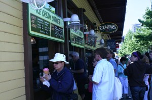 1)Tourists with ice cream: A group of tourists wait in line to buy ice cream from the Ice Cream Corner on Alaskan Way as they enjoy the sunshine by the piers.