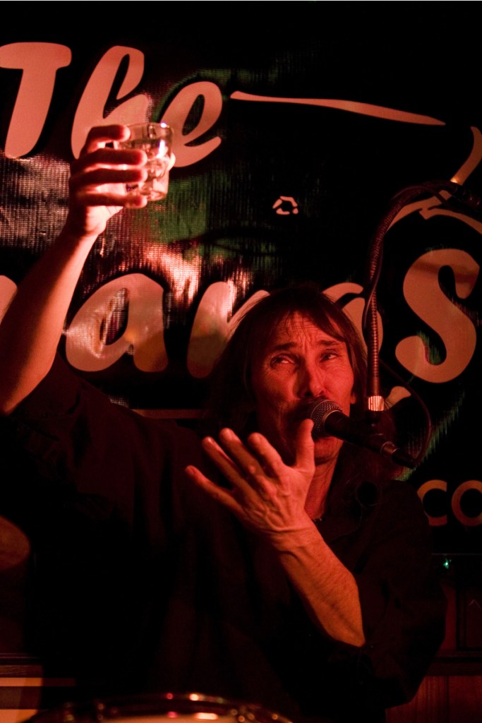 Holzman serenades his omnipresent shot glass with a makeshift spotlight on his face.