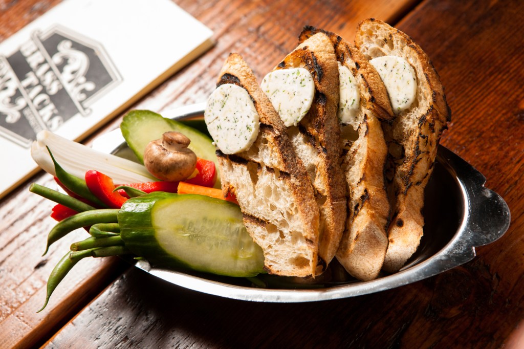 Chef Chris Opsata, top, prepares a pickle and bread dish, above, and a salad of split roasted artichoke stalks, thin radish discs, white beans, and a smattering of roasted garlic slivers as a disciplined homage to the season.