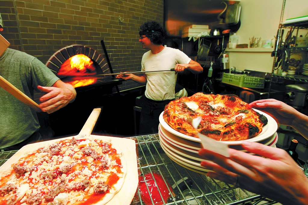 Above: Brandon Pettit unloads a pie from the wood-burning oven at Delancey Pizza in Ballard. Pettit owns the restaurant with wife Molly Wizenberg. Below: Cafe Munir’s hummus dip with hot sauce.