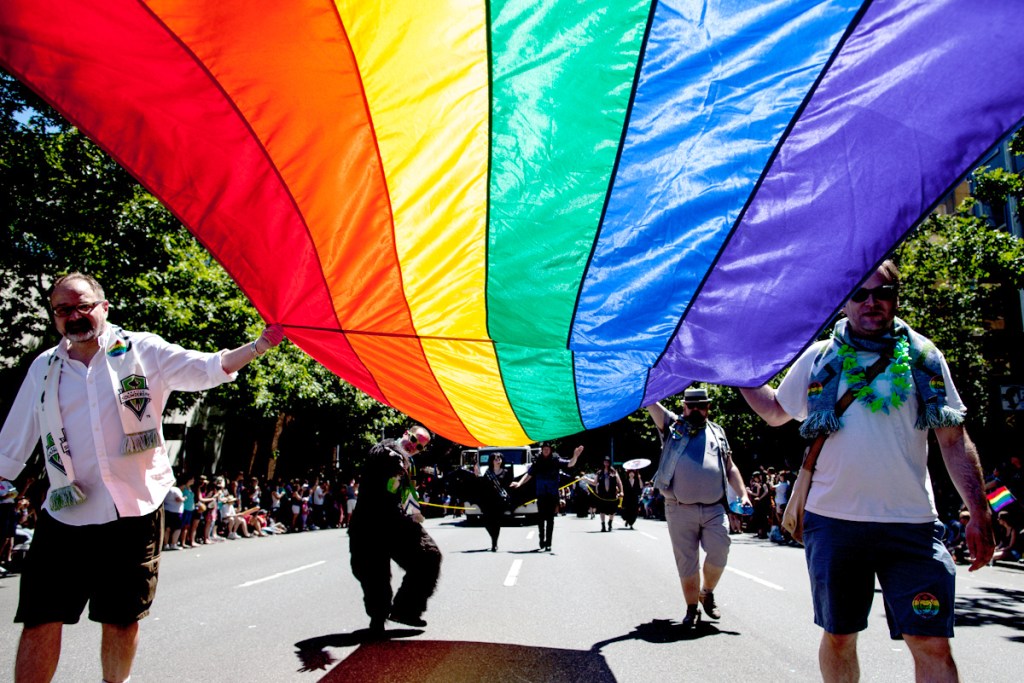 Marchers carry a large Pride flag at last weekend’s parade down Fourth Avenue, which came just four days after the U.S. Supreme Court struck down a federal law barring the U.S. government from recognizing same-sex marriages. Despite the ruling, many hurdles remain for equal treatment of gay couples.