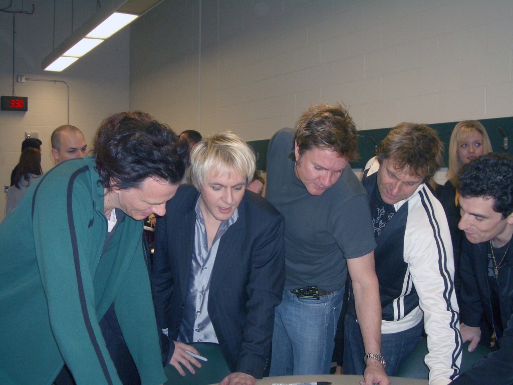 Golub (right) looks on as the band pores over a poster.
