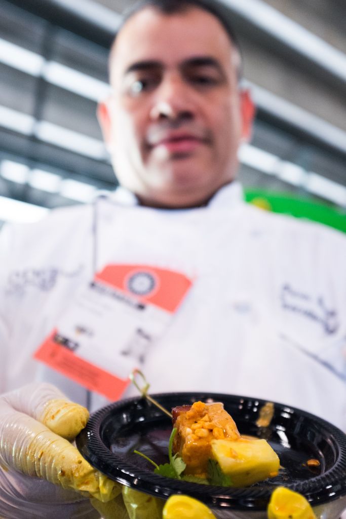 Chef Oscar Garcia holds up a braised pork belly and pineapple served with peanut sauce.