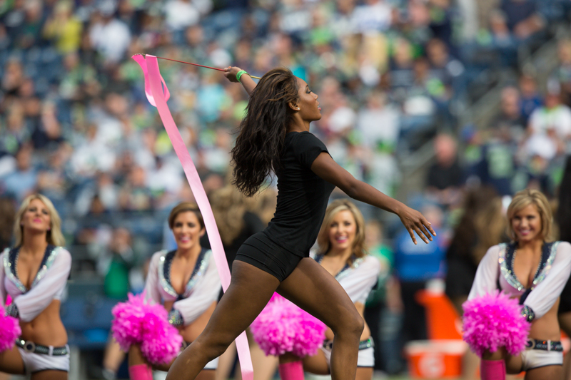A dancer twirls a large pink ribbon during halftime festivities.