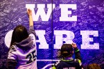12th Man fans pen condolences, prayers, and thoughts onto a giant "We Care" poster in support of Marysville, WA, the site of a recent school shooting that left four dead.