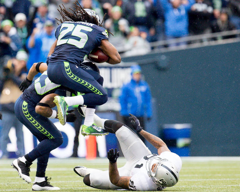 Seattle cornerback Richard Sherman leaps over Raider tight-end Mychal Rivera after intercepting a pass in the second quarter.