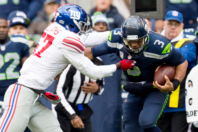 Seattle quarterback Russell Wilson fends off Giants linebacker Jacquian Williams for an 8 yard gain in the second quarter.