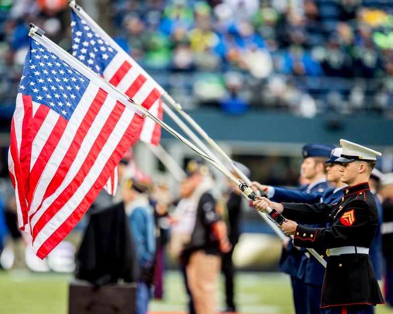 Members of the military hold up flags during a half-time ceremony.