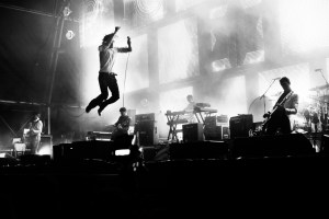 Cocker (leaping) and band perform.