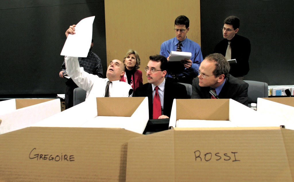 King County Councilmember Dwight Pelz examines a ballot alongside King County Elections Director Dean Logan (front center) and prosecutor’s office chief of staff Dan Satterberg (front right) as Republican Diane Tebelius (left), Democrat Will Rava (center), and Libertarian Brad Henry observe.