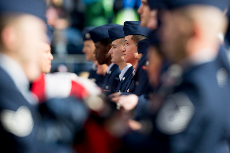 Service members hold a giant flag before the game begins.