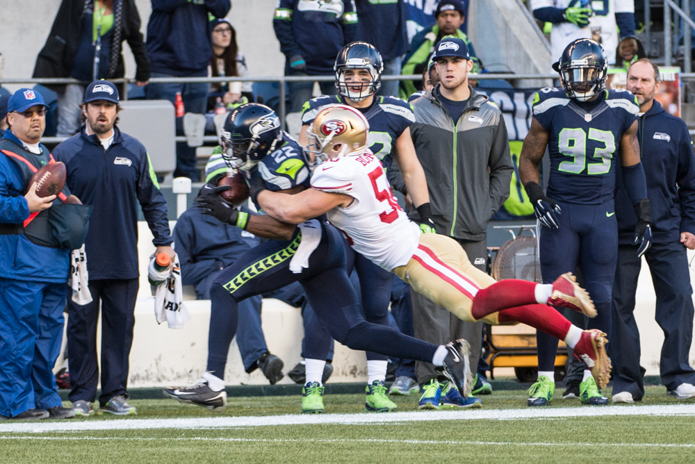 Runningback Robert Turbin is dragged down by a leaping Chris Borland at the end of the second quarter.
