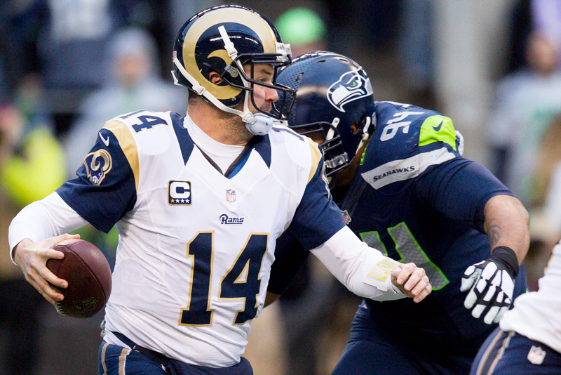 Rams' quarterback Shaun Hill looks for options downfield as Seattle defensive tackle Kevin Williams closes in for the sack.