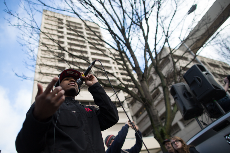 A speaker talks about the justice system in the shadow of the King County Detention Center.