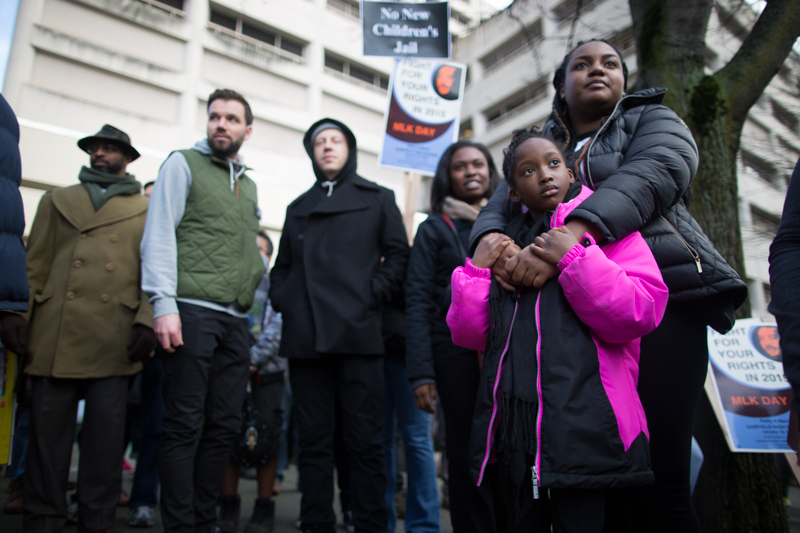Marchers listen to speakers in front of the King County Detention Center.