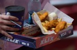 A fan carriers a box of fried chicken and fries to his seat.