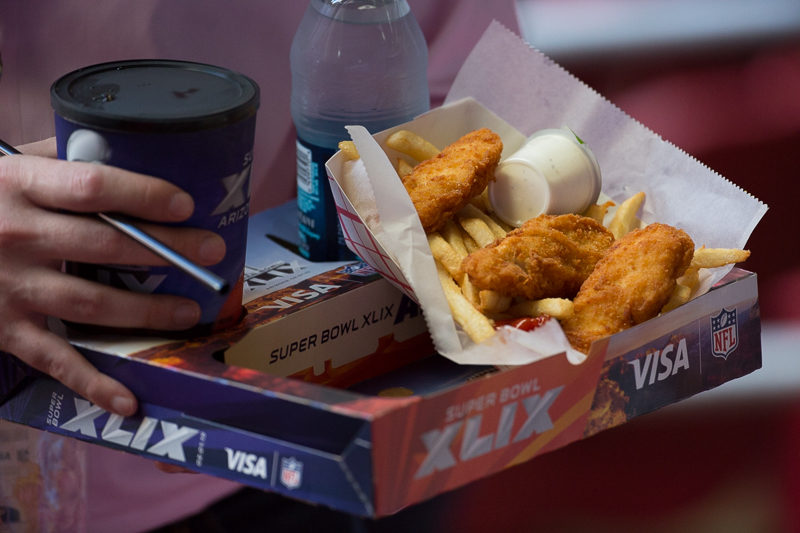 A fan carriers a box of fried chicken and fries to his seat.