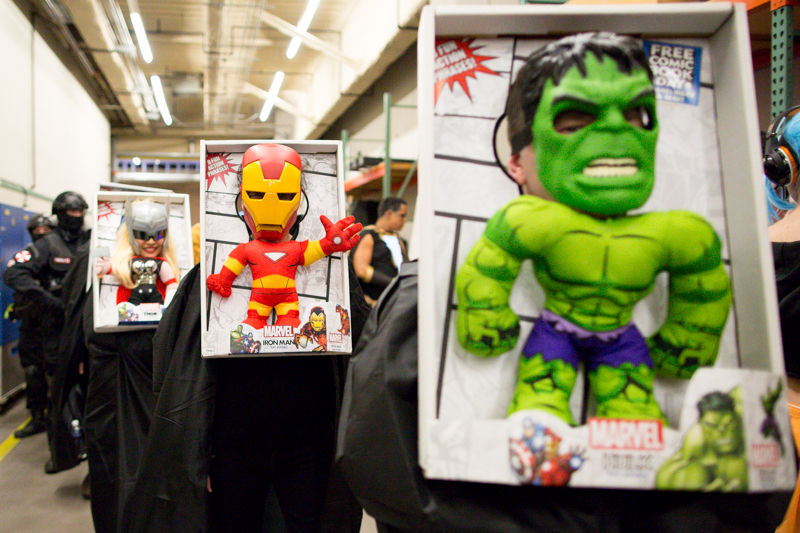 Three characters dressed as Marvel Action Hero toys walk through the service hallway before the costume contest.