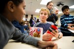 A cluster of animated students sit around a table discussing what marketing