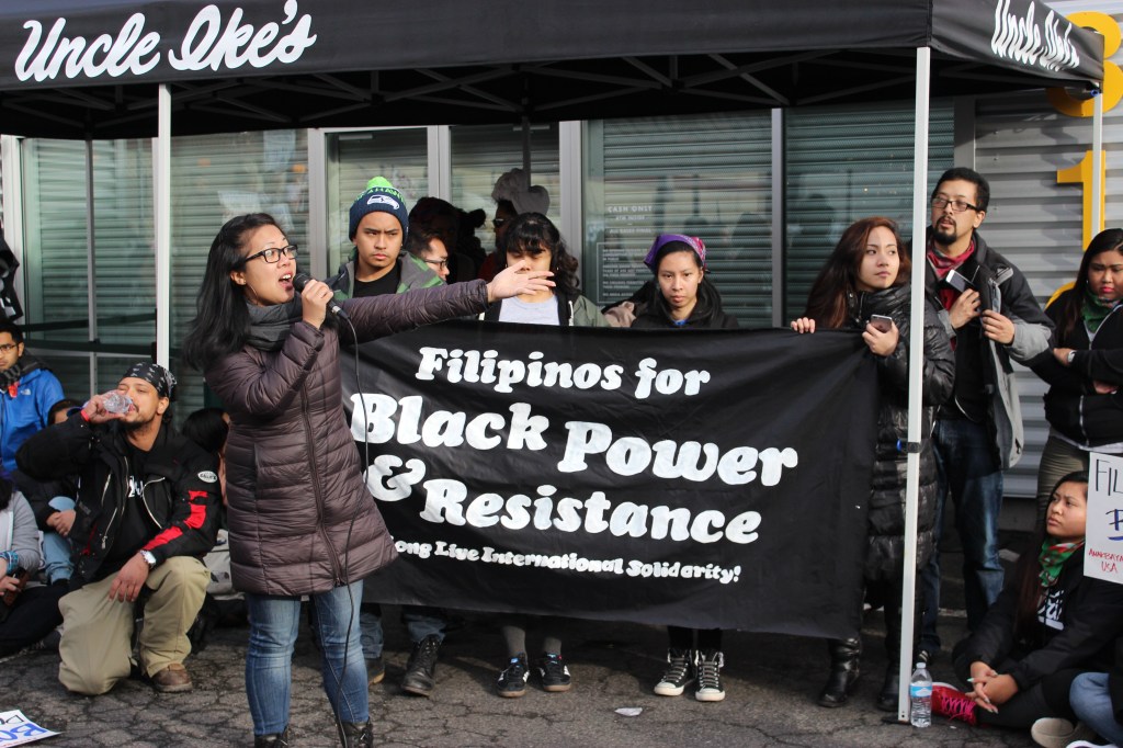 Bernadette Ellorin of Bayan USA speaks to the crowd outside Uncle Ike's. Photo by Casey Jaywork.