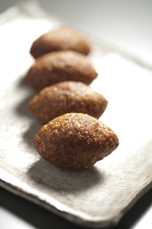 Oblong kibbeh patties, featuring impeccably-spiced beef and a pine-nut crust.