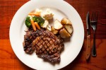 Porterhouse steak served with mixed vegetables and potatoes.