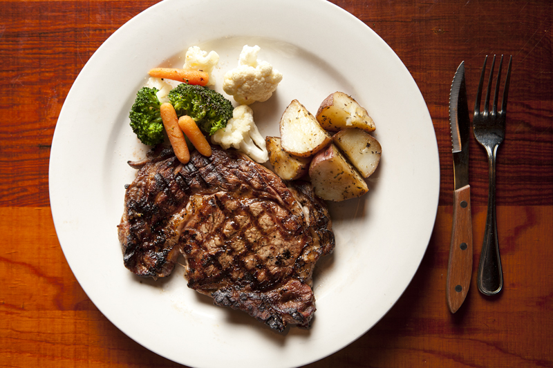 Porterhouse steak served with mixed vegetables and potatoes.
