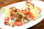 A wedge salad, crowned with two strips of a tasty candied bacon and blasted with way too much dressing.