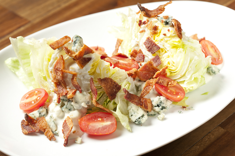A wedge salad, crowned with two strips of a tasty candied bacon and blasted with way too much dressing.