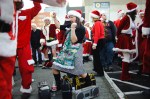 A Mrs. Claus stands over a set of boomboxes while dancing.