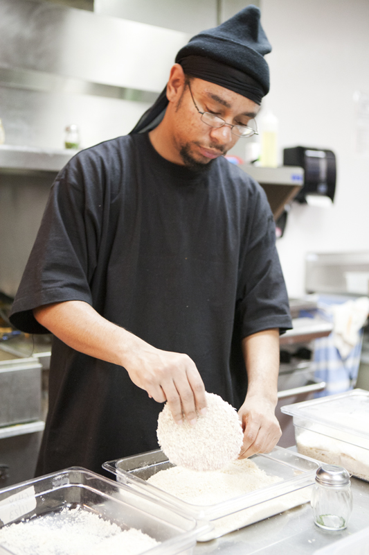 Cook Mychel breading burgers that are to be deep fried later.