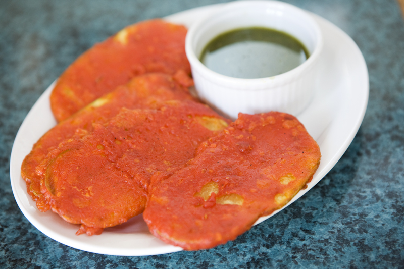 Paukara Potato fitters-thinly sliced potatoes dipped in beasan flour batter, fried and served with cilantro chutney.