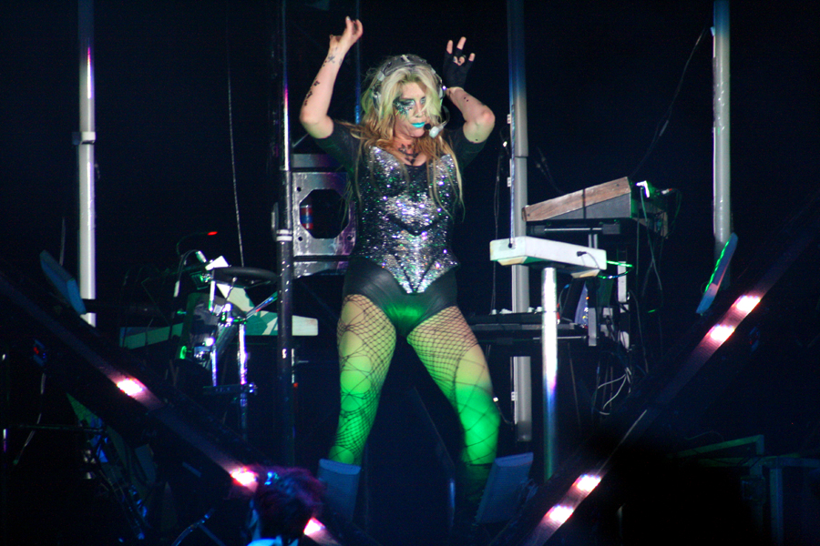 KE$HA rocks out with hands up in the air.