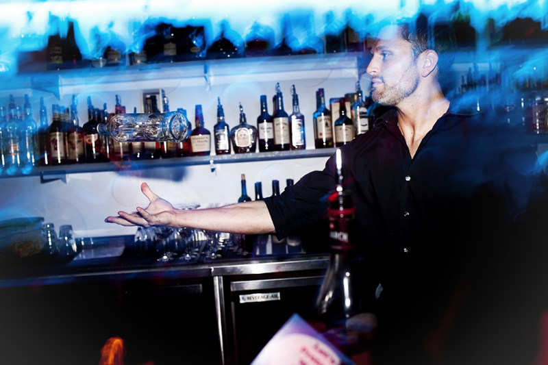 Pnk Ultra Lounge Bartender Blake Webb shows off behind the bar, turning a bottle of booze into a baton.