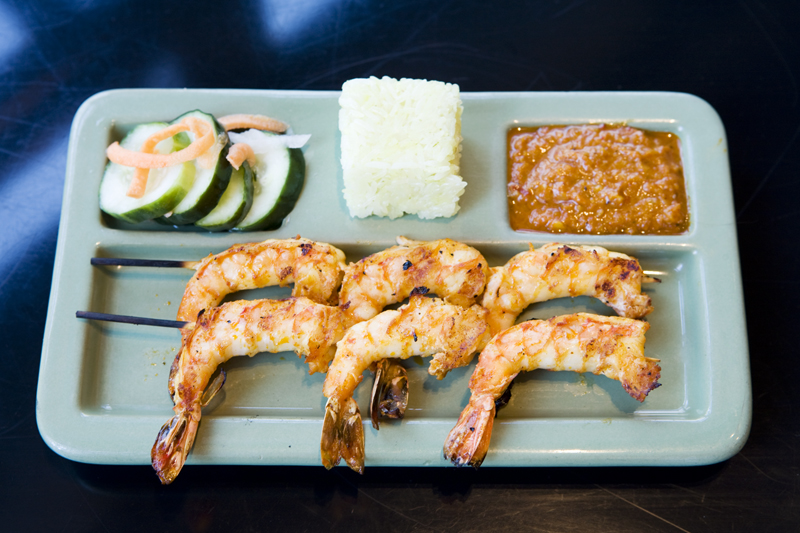 NamaE™s Prawns, marinated and grilled, served with a Cambodian dipping sauce, rice cake, and pickled cucumbers.