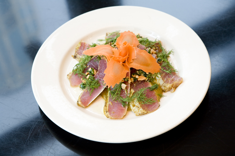 Hanoi TunaSashimi grade Ahi tuna is marinated with shallots, garlic, and turmeric. Seared rare and served with almonds, dill and scallion oil.
