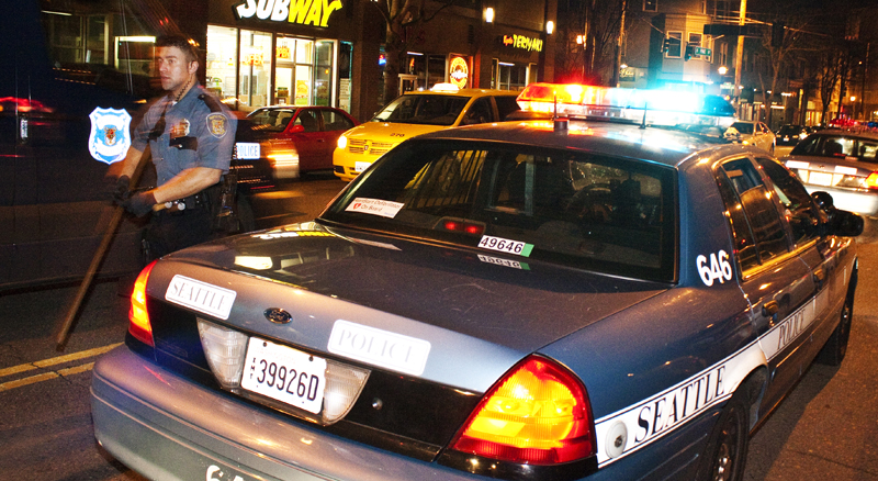 An officer prepares for crowd control after an unrelated incident causes a stir in an ally on Capitol Hill. Allegedly someone had been thrown out of a nightclub for urinating on someone else. In the same location protesters were disbanding. This incident became of interest to some of the protesters, so the club's security called the police to help control the situation.
