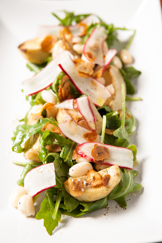 A salad of split roasted artichoke stalks, thin radish discs, white beans and a smattering of roasted garlic slivers at Brass Tacks (Photo by Joshua Huston)