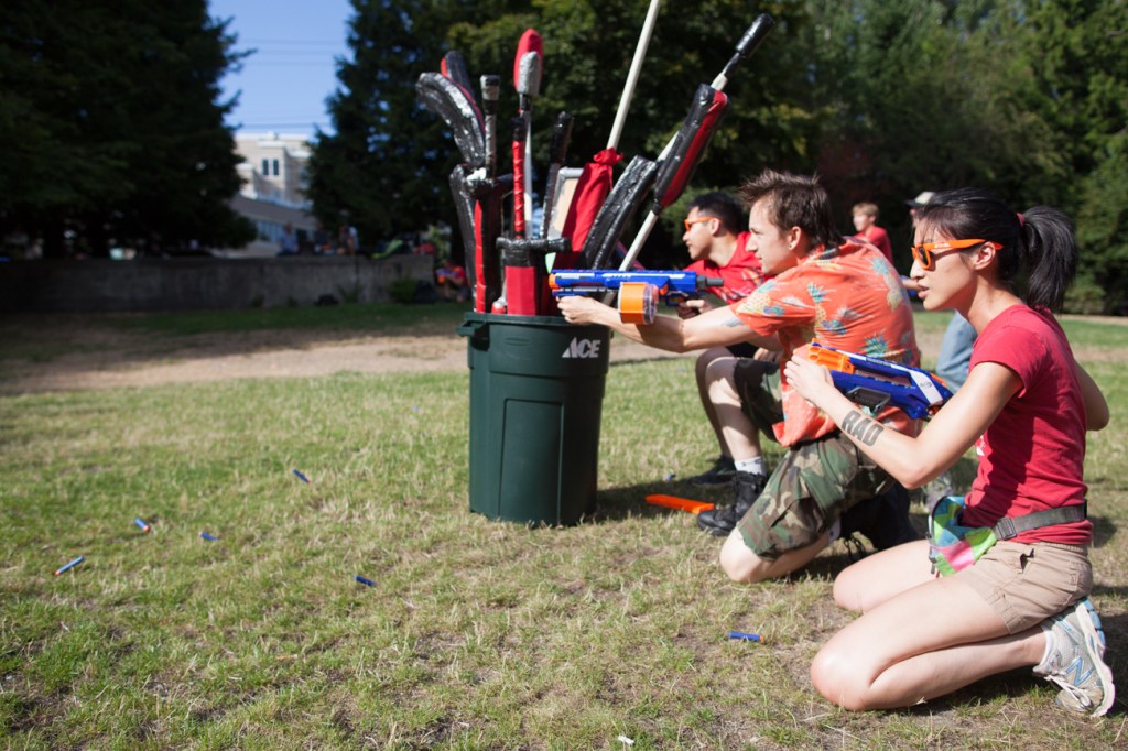 Lily Liao of Seattle crouches near teamates taking position against the advancing blue team during Reddit Seattle's 3rd Annual Nerf War Extravaganza in Gasworks Park on August 10, 2013.