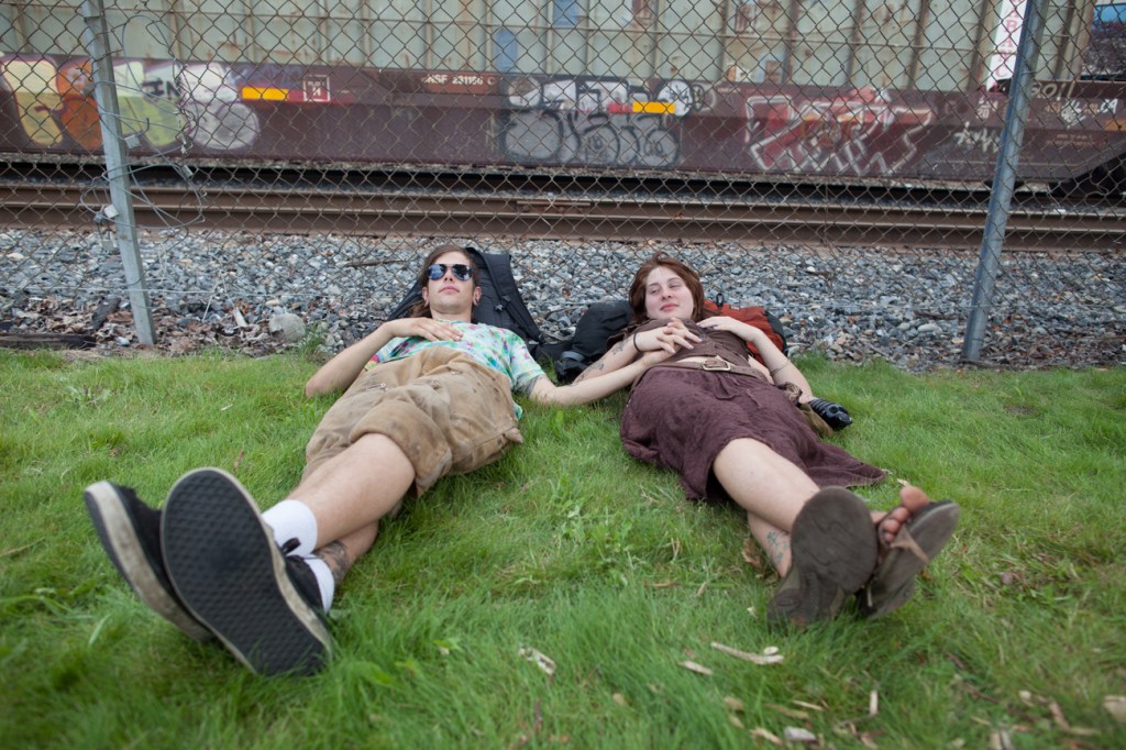 Looking relaxed a couple takes a break from the crowds on some grass.