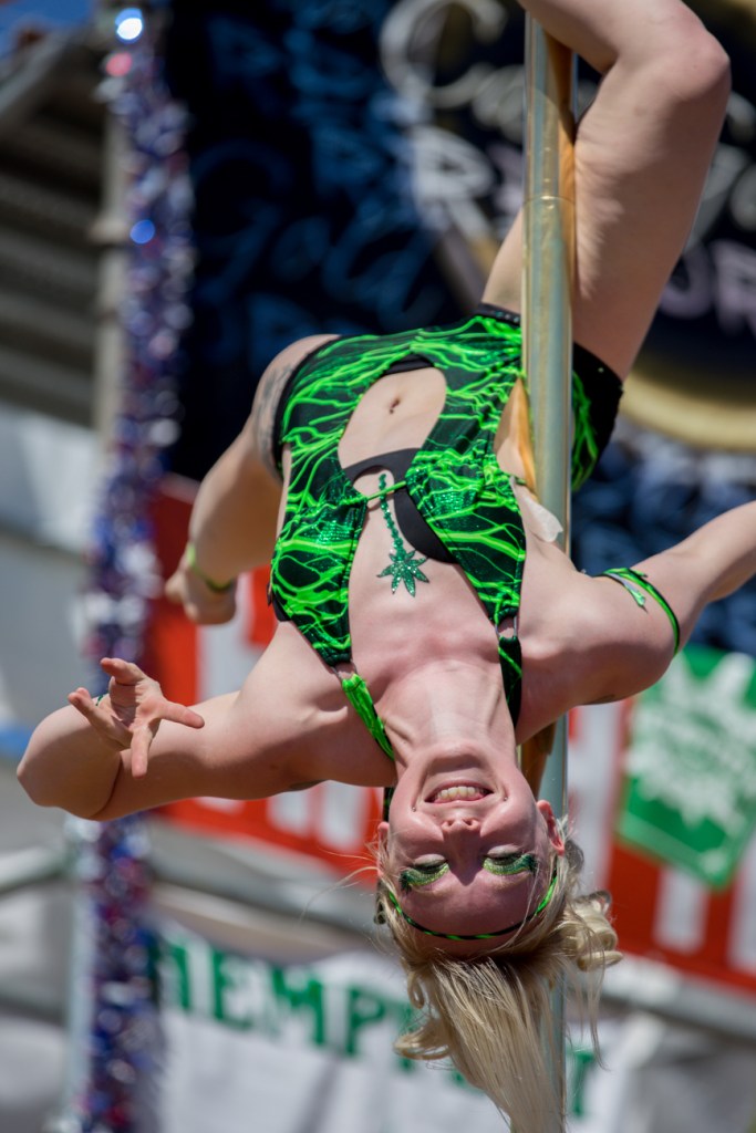 A dancer slides down a stripper pole on the main staged during a performance.