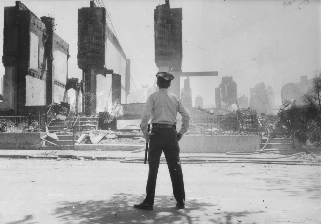 Following the fiery raid, a Philadelphia cop surveys the scene.