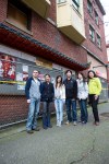 Members of the Woo family stand in front of the Community Billboard outside the fire-damaged Wah Mee building. Photo by Joshua Bessex